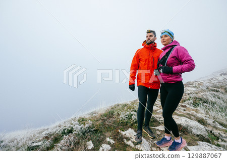 Hikers Posing on Foggy Mountain Top.Portrait of two hikers posing together on a foggy mountain top wearing outdoor gear. Hikers Posing on Foggy Mountain Top.Portrait of two hikers posing together on a foggy mountain top wearing outdoor gear. 129887067