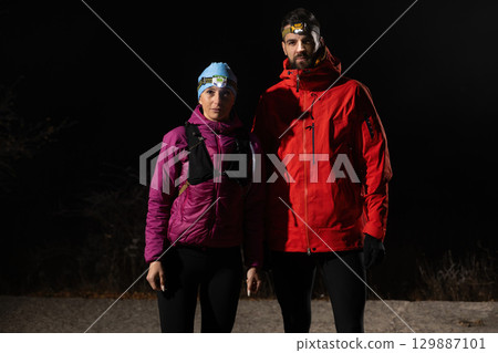 Exploring the Night Forest.Couple equipped with headlamps explore a forest in total darkness, with beams of light cutting through the night air. 129887101