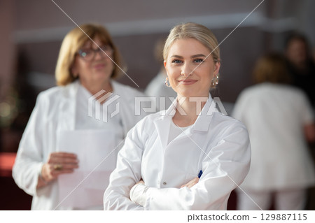 Young female doctor posing in front of medical staff 129887115