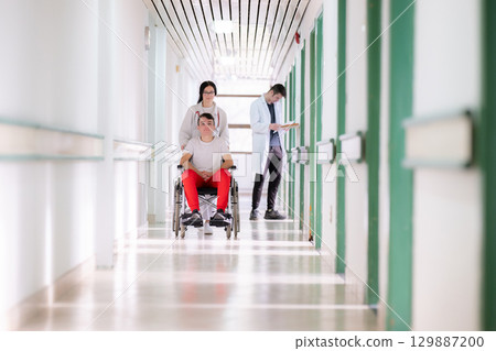 Young Male Patient in Wheelchair Assisted by Female Medical Professional 129887200