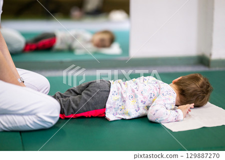 Child on Therapy Mat During SessionYoung boy on a therapy mat during a physiotherapy session, engaging in a supervised stretching activity. Child on Therapy Mat During SessionYoung boy on a therapy mat during a physiotherapy session, engaging in a supervised stretching activity. 129887270
