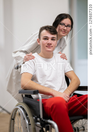 Young Male Patient in Wheelchair Assisted by Female Medical Professional 129887310