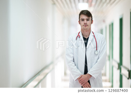 Doctor Standing in Hospital Hallway.Young male doctor standing confidently in a hospital corridor with a stethoscope. Medical professionalism concept. Doctor Standing in Hospital Hallway.Young male doctor standing confidently in a hospital corridor with a stethoscope. Medical professionalism concept. 129887400