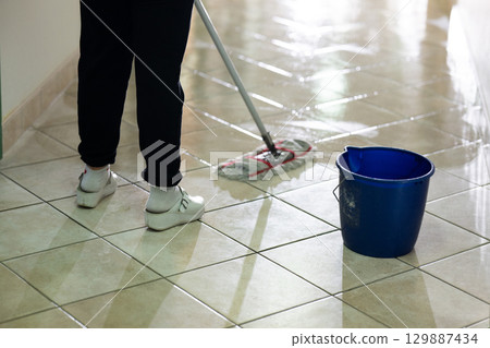 Cleaning Staff in Hospital Hallway.Female janitor standing in a hospital corridor with mop and bucket, symbolizing cleanliness and hygiene. Cleaning Staff in Hospital Hallway.Female janitor standing in a hospital corridor with mop and bucket, symbolizing cleanliness and hygiene. 129887434