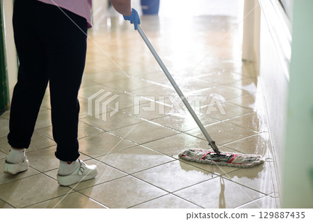 Cleaning Staff in Hospital Hallway.Female janitor standing in a hospital corridor with mop and bucket, symbolizing cleanliness and hygiene. 129887435