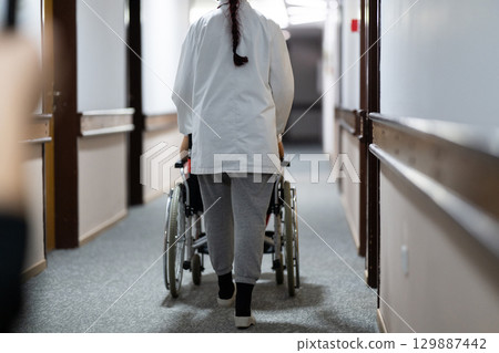 Young Male Patient in Wheelchair Assisted by Female Medical Professional 129887442