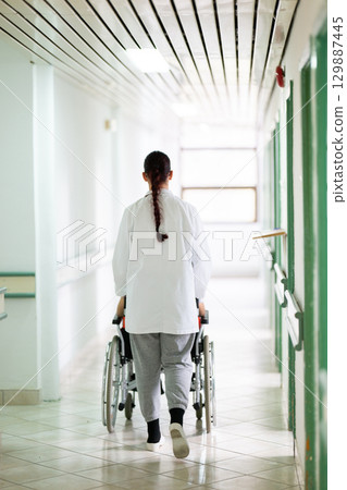 Young Male Patient in Wheelchair Assisted by Female Medical Professional 129887445