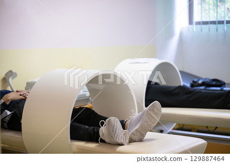 Magnet Therapy Procedure.Patients lying down with legs inside circular magnetic therapy devices during a physiotherapy session. Magnet Therapy Procedure.Patients lying down with legs inside circular magnetic therapy devices during a physiotherapy session. 129887464