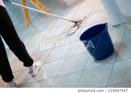 Cleaning Staff in Hospital Hallway.Female janitor standing in a hospital corridor with mop and bucket, symbolizing cleanliness and hygiene. 129887487