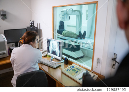 Radiologist Analyzing X-Ray Scans in a Medical Imaging Room. Radiologist Analyzing X-Ray Scans in a Medical Imaging Room. 129887495