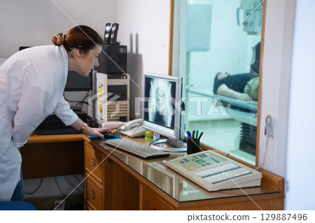 Radiologist Analyzing X-Ray Scans in a Medical Imaging Room. Radiologist Analyzing X-Ray Scans in a Medical Imaging Room. 129887496