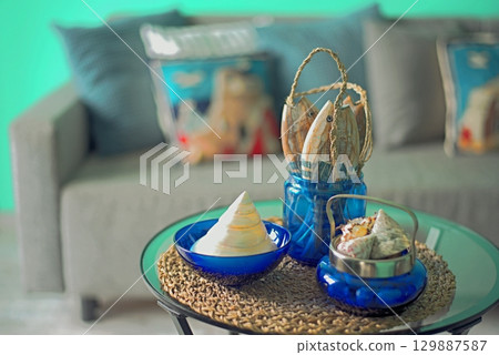 Marine style in the apartment interior - a sofa with pillows and a table with shells and fish figures. Marine style in the apartment interior - a sofa with pillows and a table with shells and fish figures. 129887587