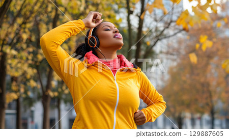 Tired African woman running outdoors in a city park on a crisp autumn morning with headphones on. Generated image 129887605