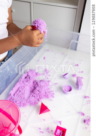 Child playing with purple kinetic sand at indoor activity table Child playing with purple kinetic sand at indoor activity table 129887608