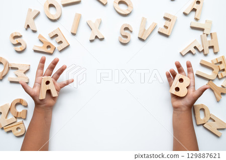Child hands holding wooden letters on white background for learning Child hands holding wooden letters on white background for learning 129887621