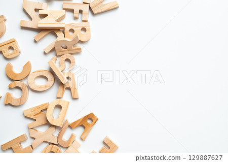 Wooden alphabet letters scattered on white background for educational and craft use 129887627