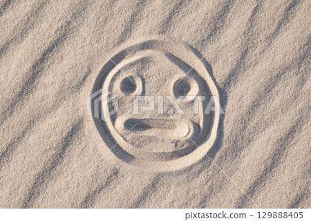 Sad and bewildered smile on sand. Negative emotions, strange feeling concept Sad and bewildered smile on sand. Negative emotions, strange feeling concept 129888405