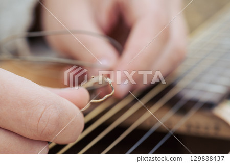 Macro shot of torm guitar string in hands of a guitarist. Changing strings in the guitar 129888437