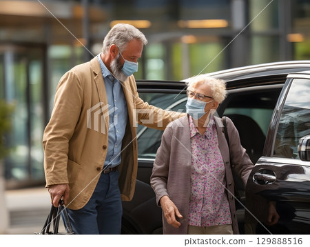 man helping elderly relative into car outside terminal man helping elderly relative into car outside terminal 129888516