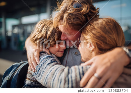 family hugging goodbye before entering airport entrance 129888704