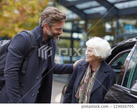 man helping elderly relative into car outside terminal 129888705