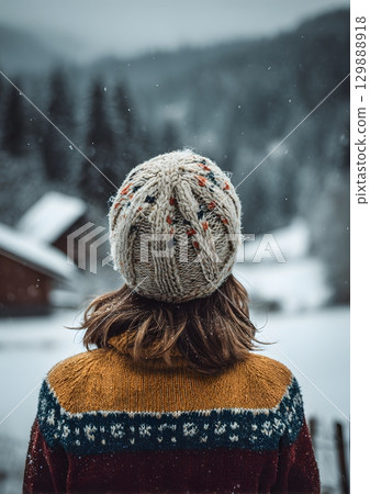 girl wearing knitted hat looking at snowy scenery 129888918