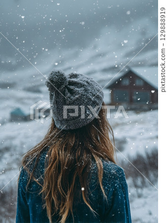 girl wearing knitted hat looking at snowy scenery 129888919