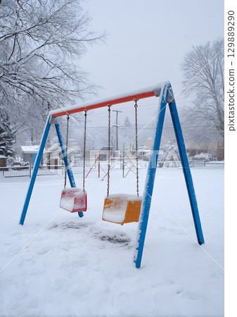 swing set in snow covered playground 129889290