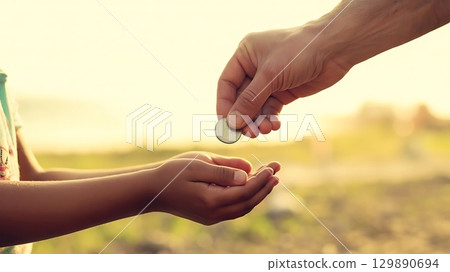 Hands exchanging coin with bright background illustrating donation aid 129890694