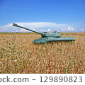 Old tank on field of yellow wheat and blue sky with clouds on the horizon. concept of war in Ukraine 129890823