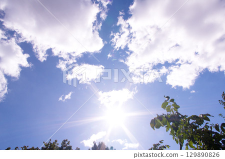 Bright sun and blue sky with clouds. Concept of abnormal heat Bright sun and blue sky with clouds. Concept of abnormal heat 129890826