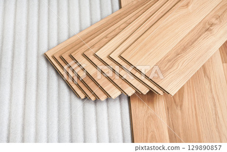 Tiles of laminated floor with wooden effect laying on white base foam, ready to be installed 129890857
