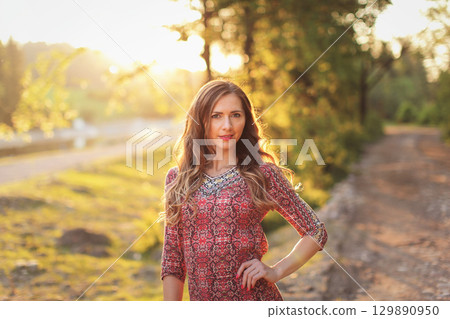 Portrait of young woman in casual summer dress, strong sunset backlight with nice bokeh 129890950