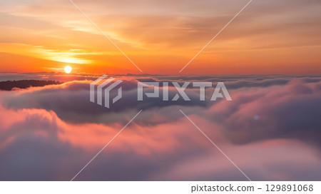 Sunrise over a sea of clouds with a vibrant orange and pink sky above it Sunrise over a sea of clouds with a vibrant orange and pink sky above it 129891068