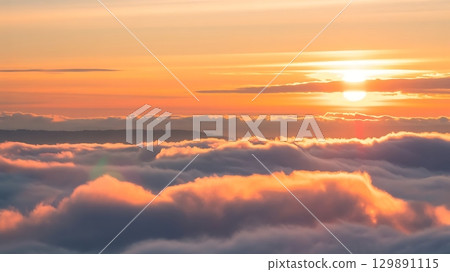 Peaceful sunrise or sunset above fluffy clouds glowing with warm hues and golden sunlight in scenic composition Peaceful sunrise or sunset above fluffy clouds glowing with warm hues and golden sunlight in scenic composition 129891115