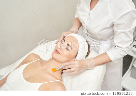 Young caucasian female relaxing during facial treatment at beauty spa clinic Young caucasian female relaxing during facial treatment at beauty spa clinic 129891233