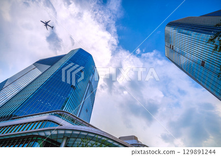 Tokyo cityscape in Japan: Aircraft passing by... Extreme heat, developed clouds over Takanawa Gateway City... = August 21st 129891244