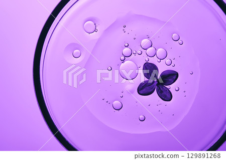 The texture of the serum in a petri dish with purple flowers. 129891268