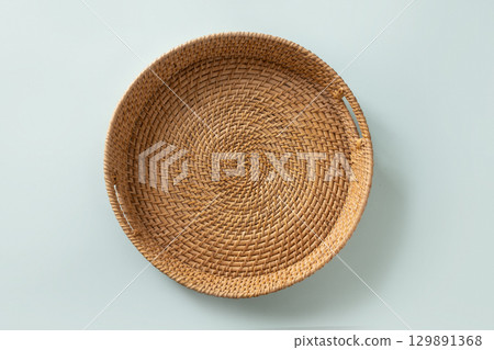 Wicker woven bamboo tray on blue background. Handmade by local craftsmen in sri lanka traditional tableware. View from above. Wicker woven bamboo tray on blue background. Handmade by local craftsmen in sri lanka traditional tableware. View from above. 129891368
