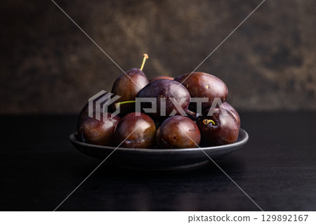 Ripe plums on black table. 129892167
