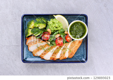 Grilled Chicken Salad Bowl with Broccoli, Avocado, Cherry Tomatoes, and Pesto Sauce 129893023