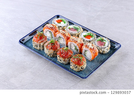 Elegant Sushi Roll Assortment with Salmon, Tuna, Sesame Crust, and Fresh Garnishes 129893037