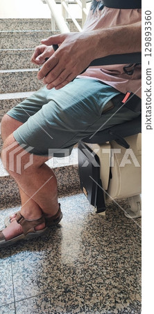 Man sitting on stairlift for mobility assistance at home. accessibility, disability support, independence, healthcare technology. 129893360