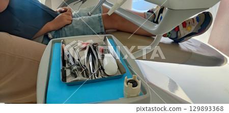 Child in dental clinic lying in chair with professional dental instruments in foreground. preventive dental measures, pediatric dental implantation, health care, hygiene, pediatric dentistry 129893368
