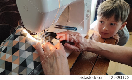 Child watching sewing on machine - DIY crafting, family bonding, handmade textiles, slow living home studio, sustainable fashion learning moment Child watching sewing on machine - DIY crafting, family bonding, handmade textiles, slow living home studio, sustainable fashion learning moment 129893370