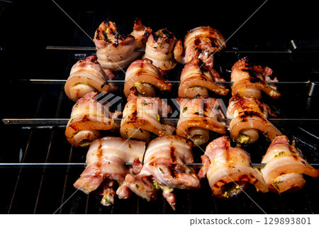 Grilled pork belly skewers cooking on barbecue grill 129893801