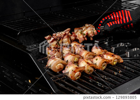 Grilled pork belly skewers cooking on barbecue grill 129893805