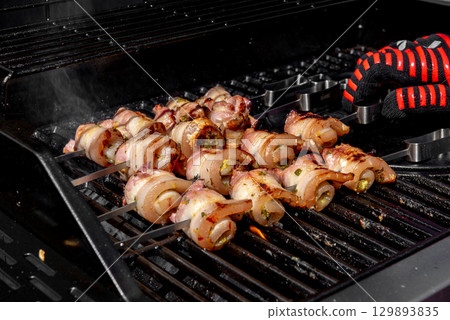 Grilled pork belly skewers cooking on barbecue grill 129893835
