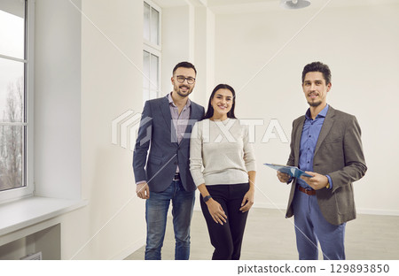Young happy couple looking a new house with realtor. Real estate market concept. Young happy couple looking a new house with realtor. Real estate market concept. 129893850