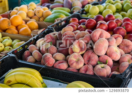 Colorful selection of fresh fruits, including peaches, bananas, and apples, on display at a farmers market. Vibrant and healthy produce ideal for vegetarians, vegans, and healthy lifestyle choices. Colorful selection of fresh fruits, including peaches, bananas, and apples, on display at a farmers market. Vibrant and healthy produce ideal for vegetarians, vegans, and healthy lifestyle choices. 129893870